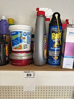 Shelf with assorted insect sprays, cleaning solutions, adhesive bucket, and boxes.