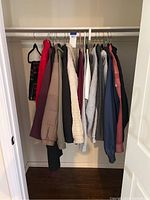 Full view of jackets and sweatshirts hanging on closet rod, showing various colors and styles.