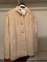 Front view of vintage cream ladies car length jacket showing button closure and fur exterior.