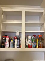 Laundry and cleaning supplies on bottom shelves of white cabinet