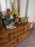 Front view of maple wood dresser with nine drawers showing metal handles and surface with minor scratches. Objects on top of dresser not included.