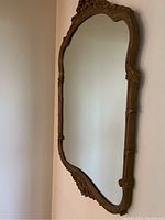 Full side view of vintage gold painted wall mirror showing carved detailed wooden frame.