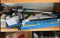 Shelf with assorted tools, packing trays, wall bar with hand shower, pruners, metal tools, and grabber tool