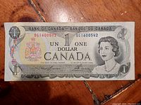 Front side of vintage Canadian one dollar bill from 1973 showing Queen Elizabeth II portrait, coat of arms, and serial numbers.