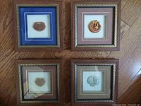 Four framed shadow box art pieces laid flat showing carved ornaments and mats