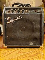 Front view of the black Squier SP.10 amplifier showing controls, Squier logo, speaker grille, and power button.