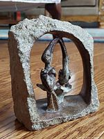 Side view of the handcrafted stone sculpture showing the two toucans inside a rectangular stone frame with natural texture.