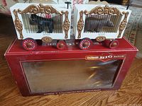 Two vintage Bachmann Big Haulers cage cars with red wheels and gold decorative wood frames sitting on original box