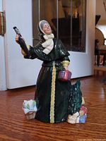 Front view of the Royal Doulton Christmas Parcels figurine showing the woman with raised umbrella and the parcels at her feet.