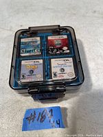 Photo of four Nintendo DS game cartridges in a blue and black Nintendo DS plastic storage case with clear hinged lid, showing front labels.