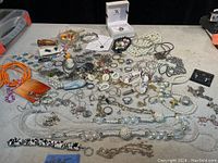 Full overview of costume jewellery lot spread on table with various necklaces, bracelets, brooches, and earrings in multiple materials and colors.