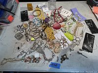 Overview photo showing the entire assortment of costume jewelry items spread out on a table, including necklaces, bracelets, earrings, brooches, and pendants.