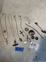 Photo showing the full collection laid out including necklaces with various pendants, earrings, bracelet, small bowl, and spoon.