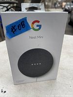 Front of Google Nest Mini retail box showing charcoal color speaker image with Google Nest Mini branding and a blue sticker labeled #08.