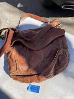 Overall front view of the worn brown leather vintage Fossil purse with flap and adjustable shoulder strap