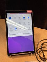 Front view of Lenovo tablet powered on showing Android quick settings menu on screen.