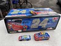 Photo of the boxed Jeff Gordon 1:24 stock car alongside two tin toy cars showing the packaging and product condition