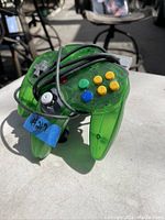 Green Nintendo 64 controller with the cord wrapped around it, showing colorful buttons and translucent casing.