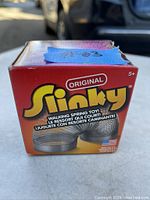 Photo of a sealed box of the Original Slinky metal coil walking spring toy with original branding and product information.