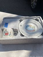 Set in original packing tray, showing the cup, bowl, and plate all with Peter Rabbit illustrations and text.