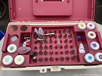 Opened plastic case showing multiple metal and plastic decorating tips along with several small containers of colored gels arranged neatly in slots.
