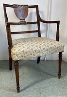 Front angled view of antique mahogany English armchair showing wood frame, carved armrests, and floral upholstered seat.