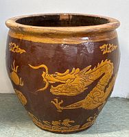 Front view of large antique ceramic planter showing prominent yellow dragon motif on brown glaze.