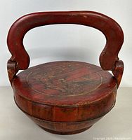 Front angle view of the handcrafted Asian wooden basket with handle and painted lid showing design details.