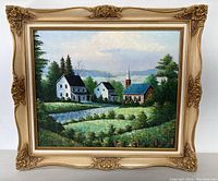Full view of the framed landscape painting showing two white houses, a church, trees, and water under a cloudy sky.