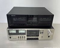 Photo showing two vintage cassette decks stacked: Nikko ND100W on top with black casing and dual cassette bays, Telefunken TC 650M below with silver front and analog VU meters.