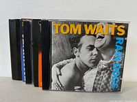 Tom Waits CDs including Rain Dogs and other albums stacked side by side showing front covers.