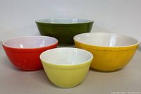 Four Pyrex nesting bowls arranged nested inside each other and also placed side by side showing each bowl individually.
