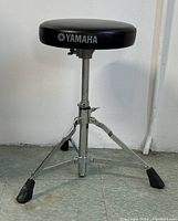 Photo of a vintage Yamaha adjustable drum throne stool with a round padded black seat and chrome tripod base on a tiled floor.