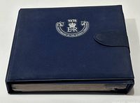 Blue binder with commemorative embossed logo for 1978 25th Anniversary of the Queen's Coronation, clasped closed.