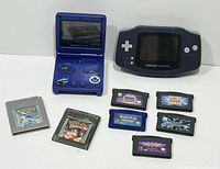 Two handheld consoles (Game Boy Advance SP and original Game Boy Advance) with seven cartridges laid out