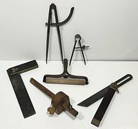 Full set of antique measuring and artist tools including dividers, calipers, marking gauge, L-square, and roller
