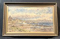 Full view of the framed watercolour painting showing the coastal scene, sky, and sea with rocky shore and buildings.