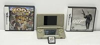 Nintendo DS Lite gold console in open position with Zoo Tycoon 2 DS game cartridge placed in front, flanked by game cases for Zoo Tycoon 2 and 007 Quantum of Solace.