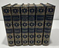 6 vintage decorative dark blue leather bound books with gilt spine detailing, showing titles and authors on spines.