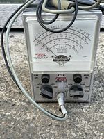 Front view showing analog needle meter with EICO branding, dials for function, range, zero adjustment, and ohms adjustment, and connected test probe cable.
