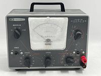 Front view showing full device with handle, large meter, multiple knobs, and ports.