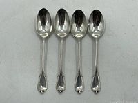 Photo of four sterling silver spoons with leaf motif handles against white background.