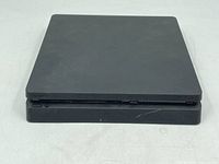 Front view of Sony PS4 Slim console showing button and distressed surface.