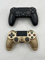 Top view of two Sony PlayStation DualShock 4 controllers, one black and one gold, showing all buttons and analog sticks.