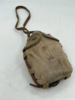 Front-angle photo showing the canvas canteen with leather straps and fabric wear stains.