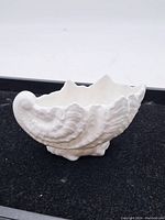 Side angle showing detailed textured seashell shape and scalloped edges of the porcelain dish.