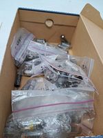 Cardboard box containing multiple vintage radio tubes in clear plastic zip bags, some labeled.