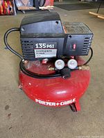 Front view of red Porter Cable 6 gallon air compressor showing the black motor housing with on/off switch and pressure ratings label (135 PSI, 2.6 SCFM @ 90 PSI, 2 HP).
