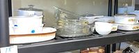 Shelf showing multiple stacks of vintage baking dishes including CorningWare and Pyrex