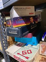 Stacked board games including Monopoly, Pictionary, Carpool Karaoke, and That's What She Said